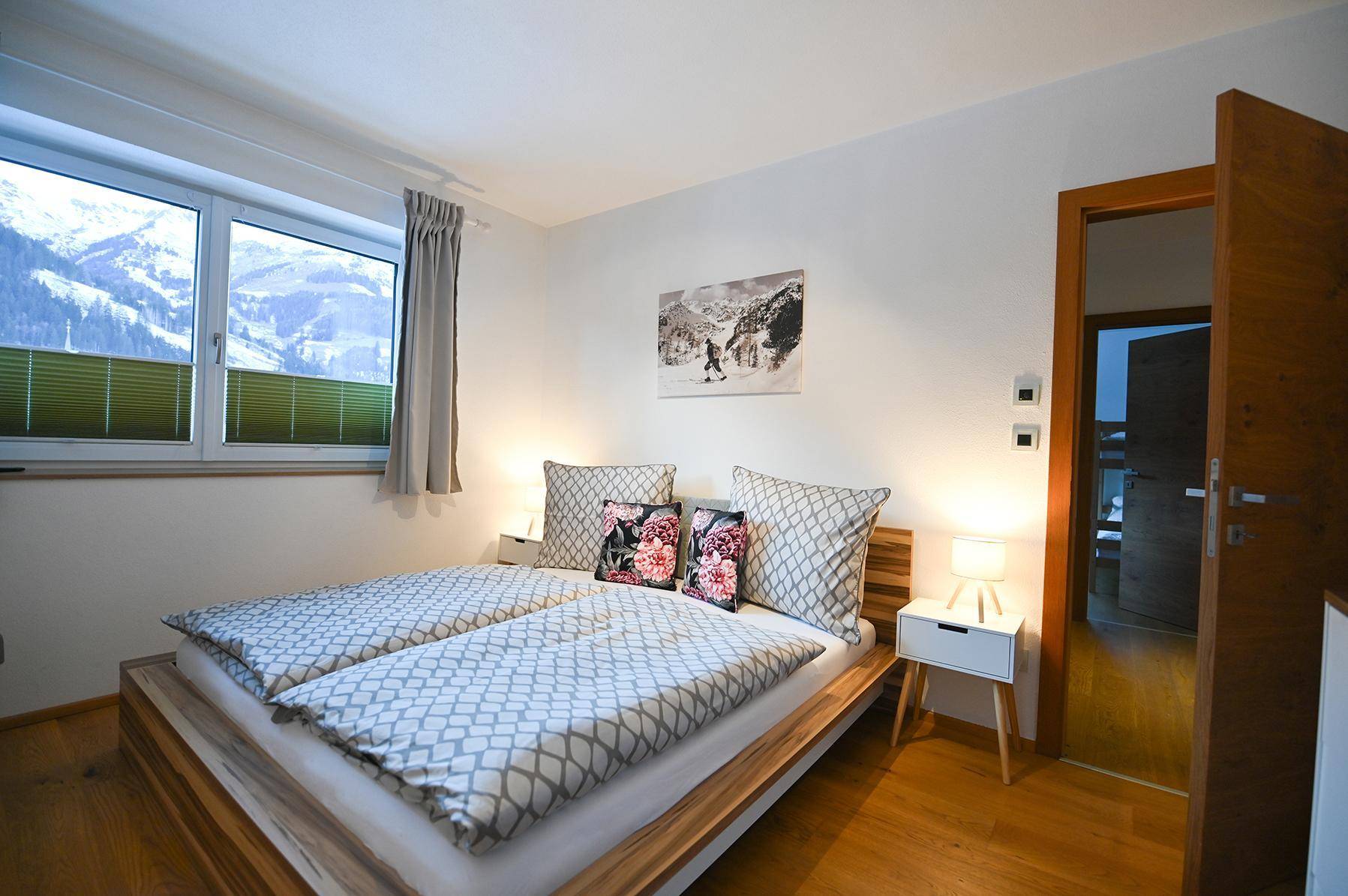Gemütliches Schlafzimmer mit Doppelbett, Holzrahmen und Fenster mit Bergblick.