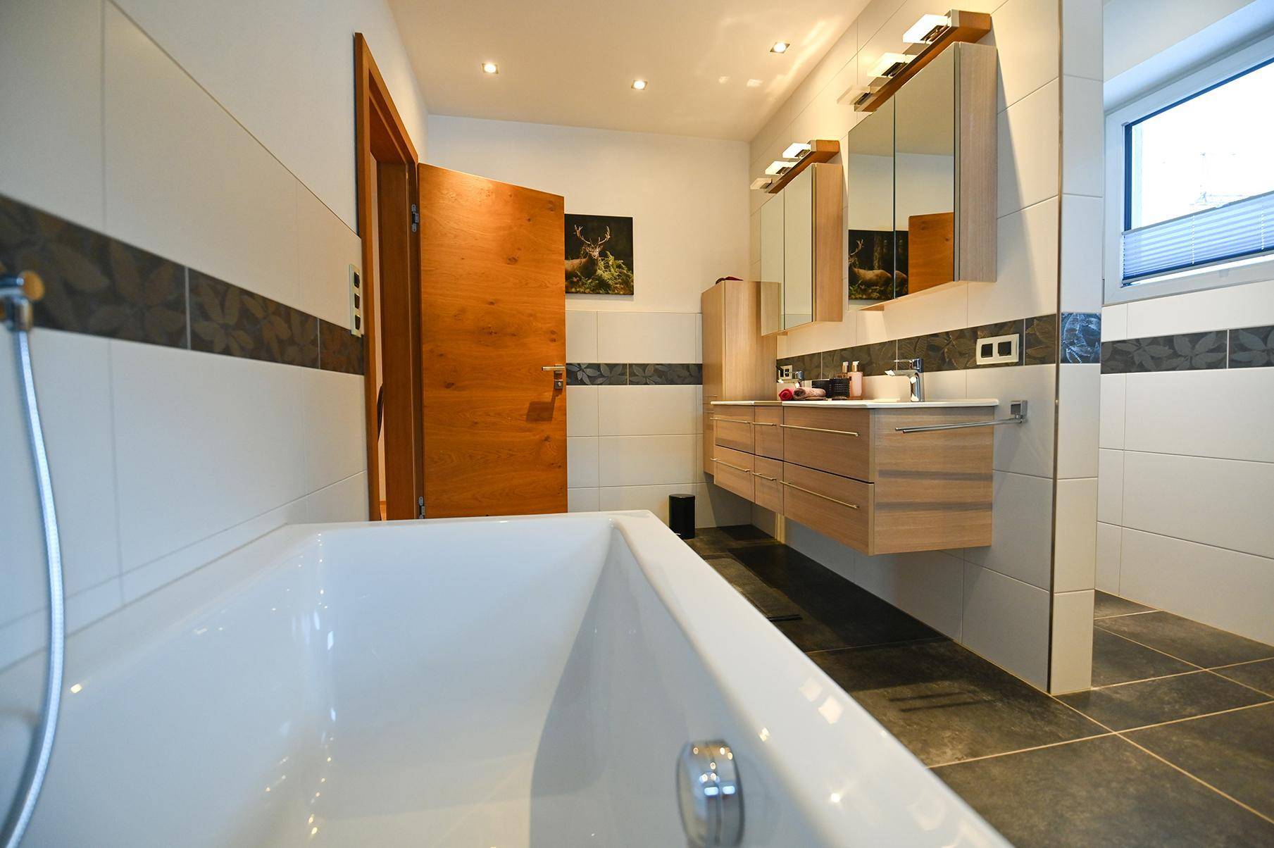 Geräumiges Badezimmer mit Badewanne, Doppelwaschbecken und modernen Armaturen.
