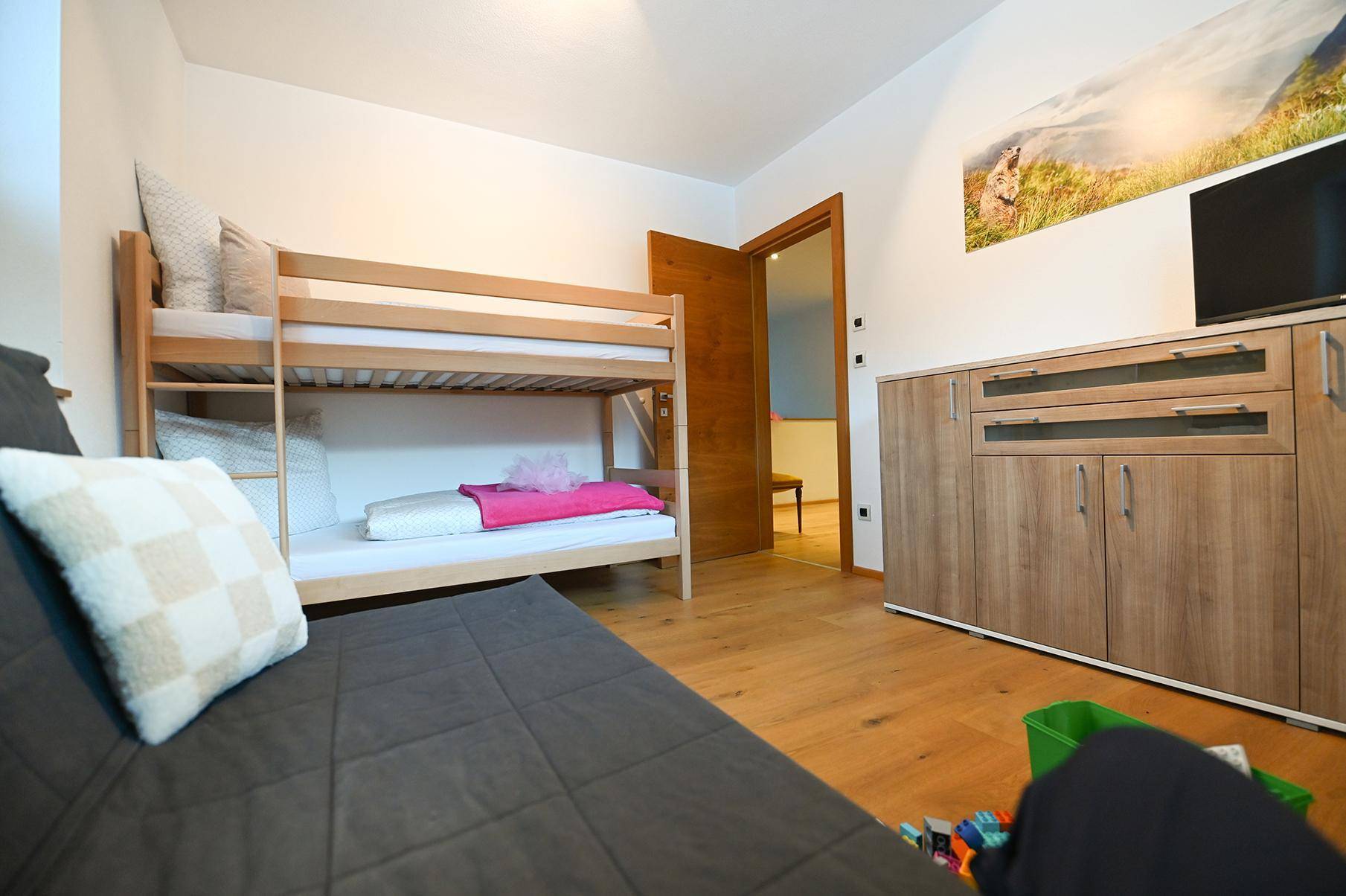 Kinderzimmer mit Etagenbett, Schlafsofa und Holzschrank, ideal für Gäste oder Familien.
