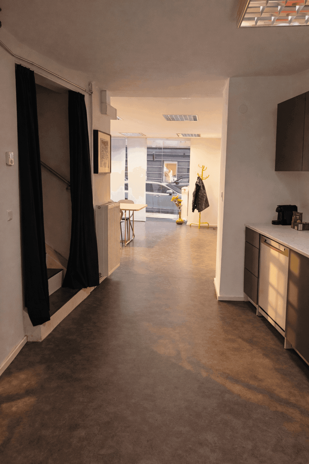 Langer Flur mit dunklem Boden, Garderobe und Blick auf den Eingangsbereich.