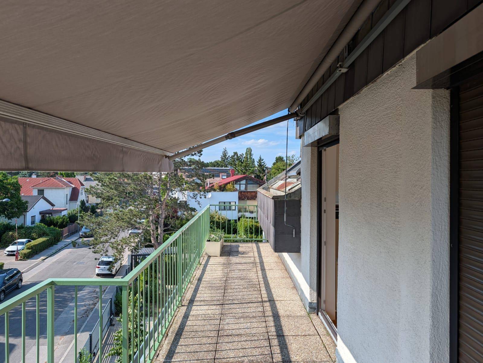 Geräumiger Balkon mit Markise und weitem Blick über die Dächer der Nachbarschaft.