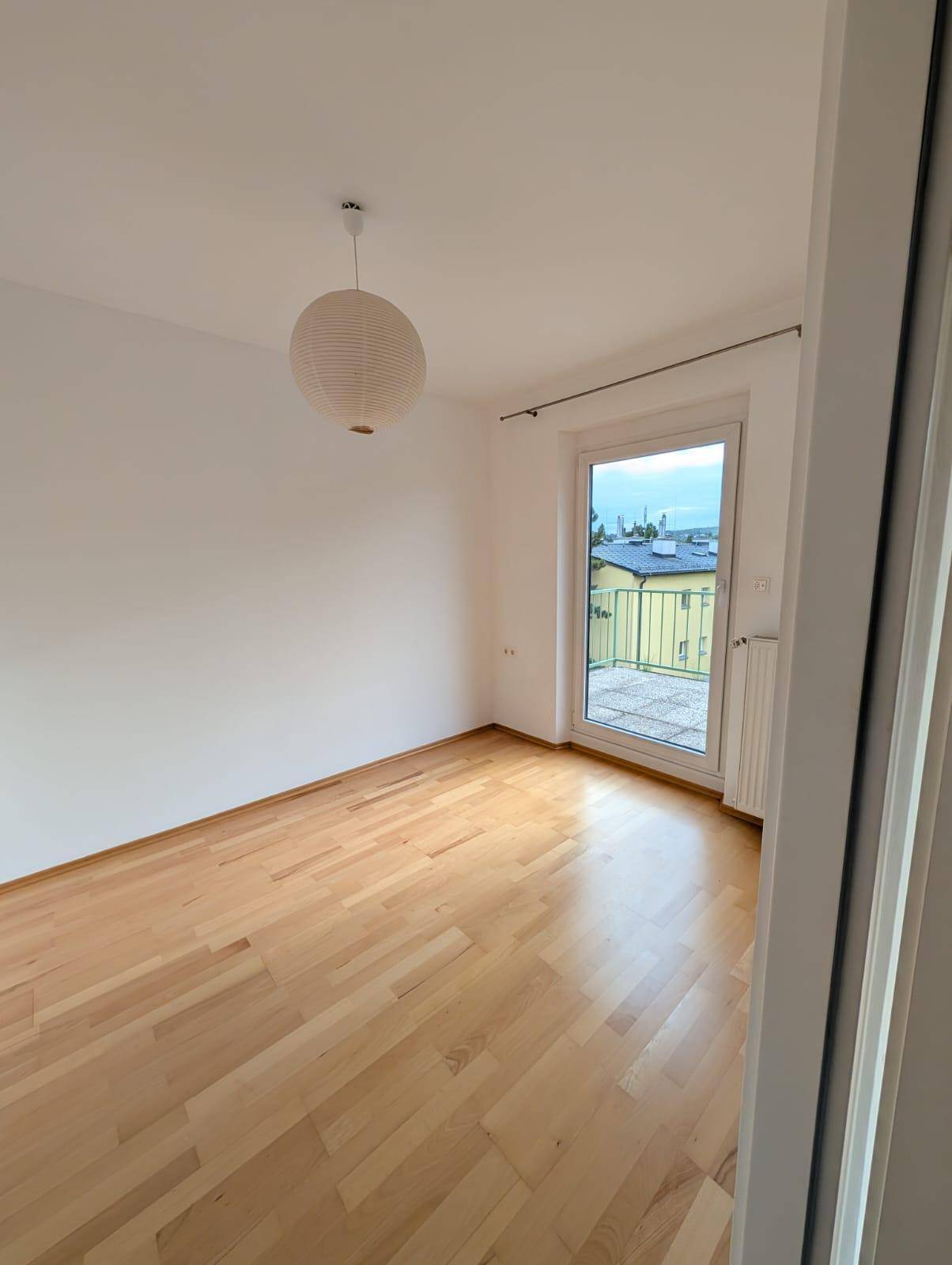 Helles Schlafzimmer mit Holzboden und direktem Zugang zum Balkon.