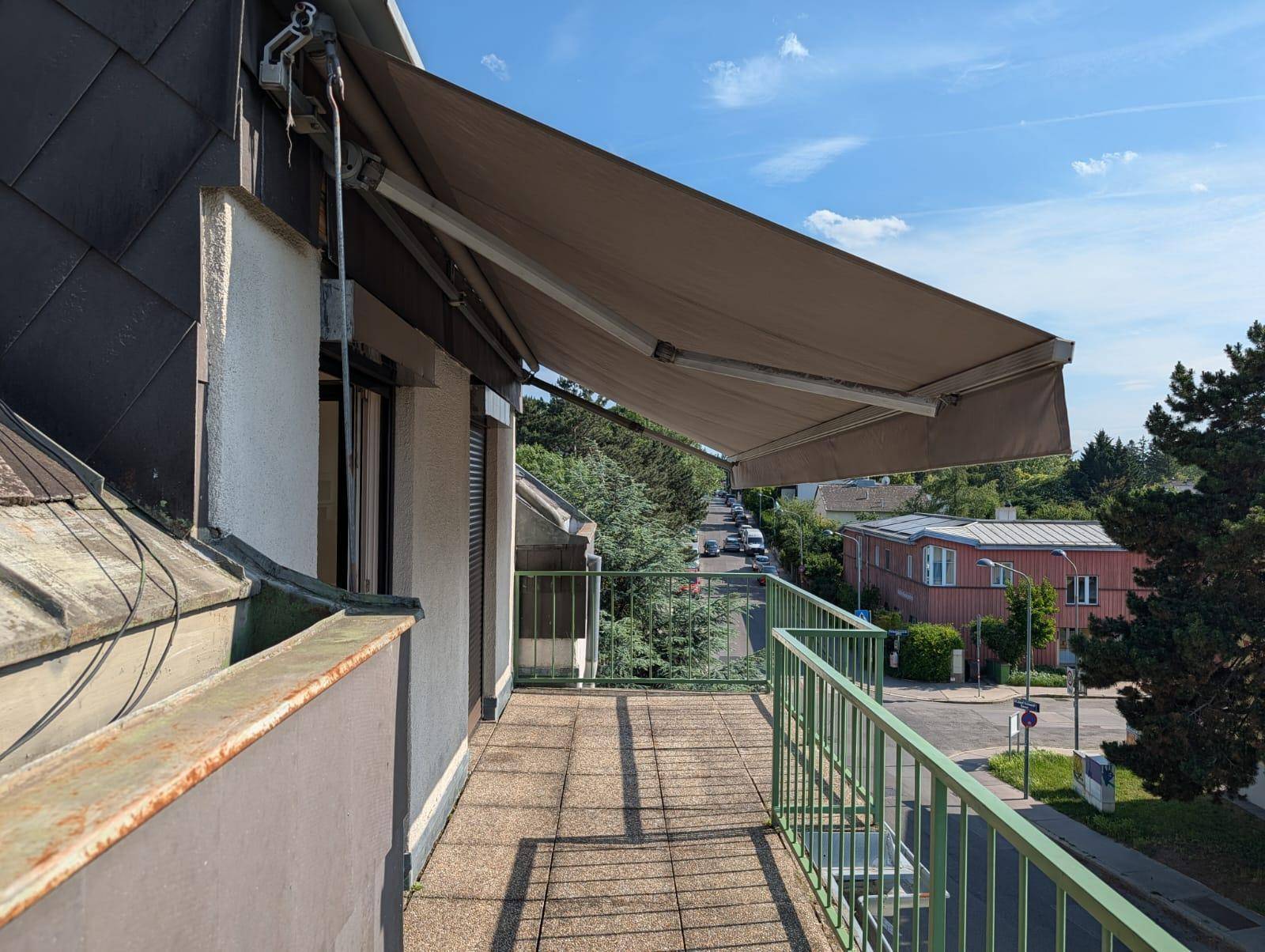 Langer Balkon mit Markise und Blick auf die umliegende Wohngegend.