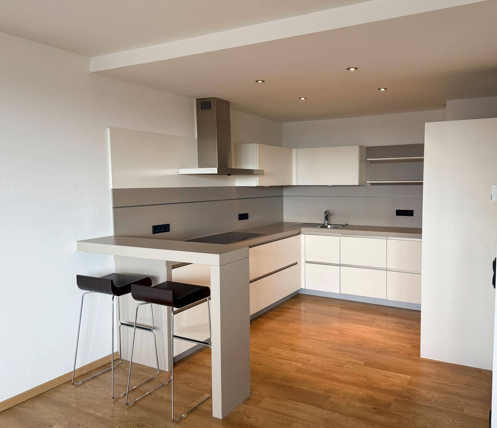 Moderne Küche mit weißen Schränken, grauen Arbeitsplatten und einer Frühstücksbar.