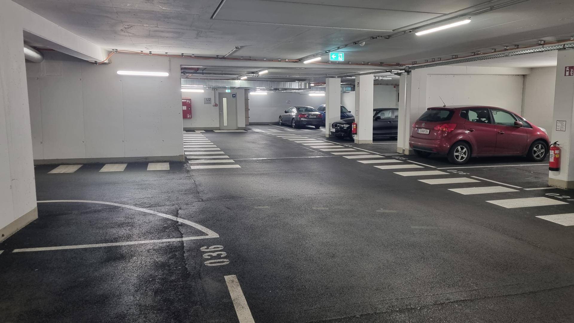 Geräumige Tiefgarage mit markierten Parkplätzen und mehreren abgestellten Fahrzeugen.