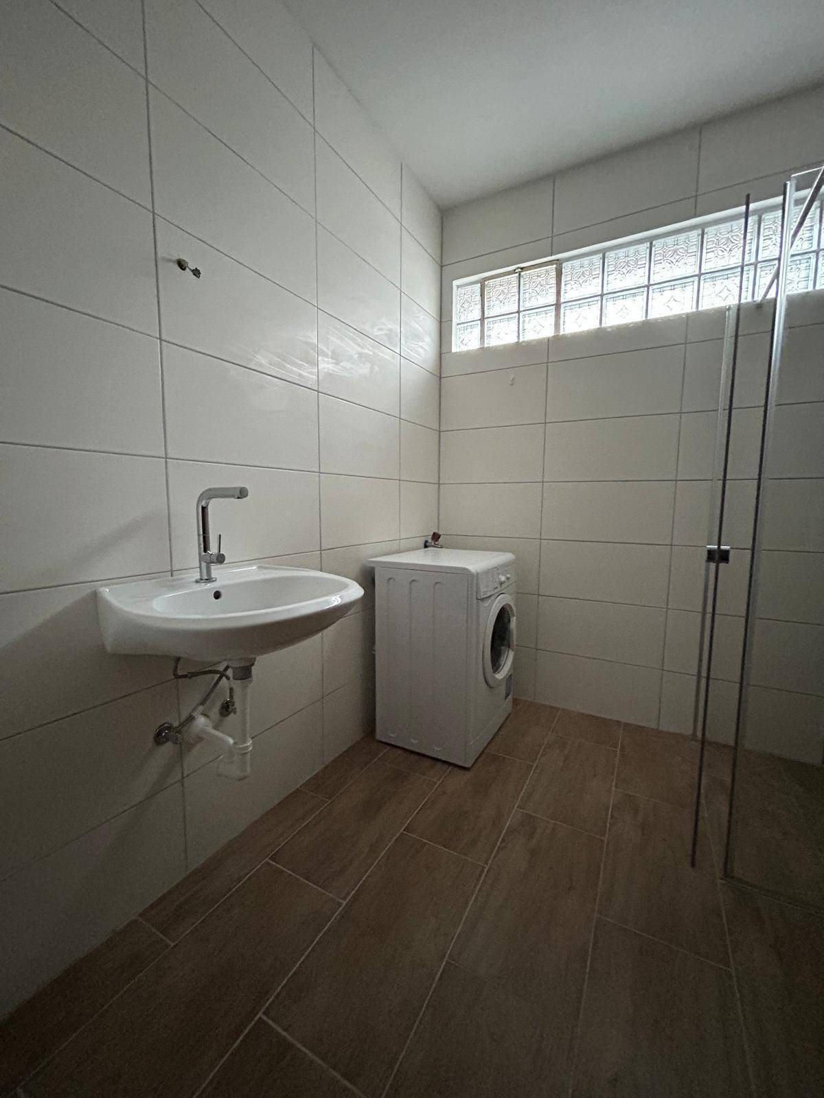Funktionaler Hauswirtschaftsraum mit Waschmaschine, Waschbecken und Fliesenboden.