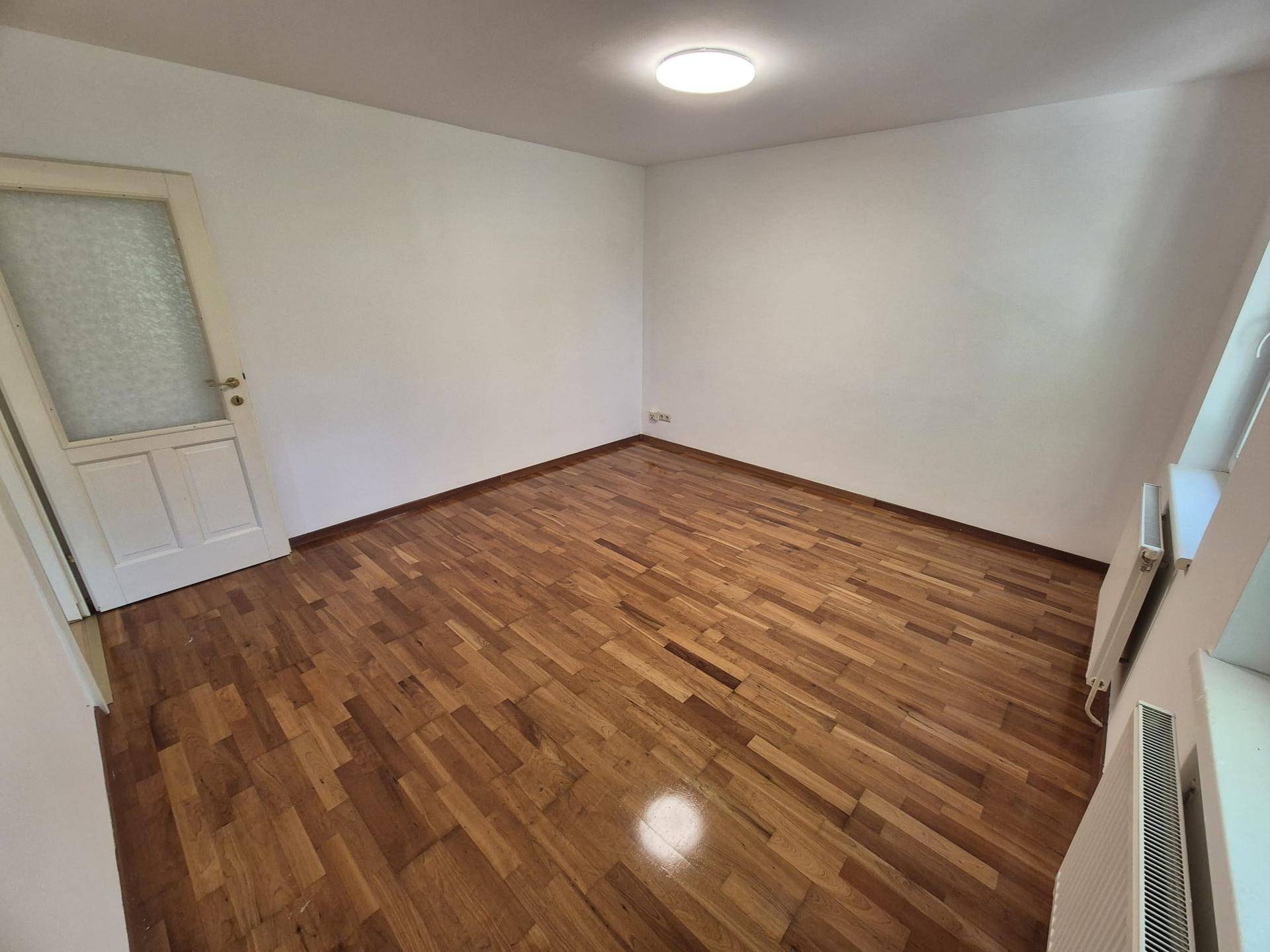 Ruhiges Zimmer mit Parkettboden und Heizkörper, geeignet als Schlaf- oder Gästezimmer.