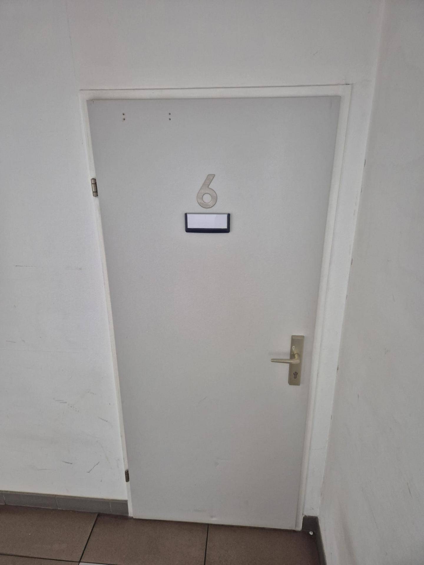 Weiße Wohnungstür mit der Nummer sechs, die den Eingang zu einer Wohneinheit markiert.