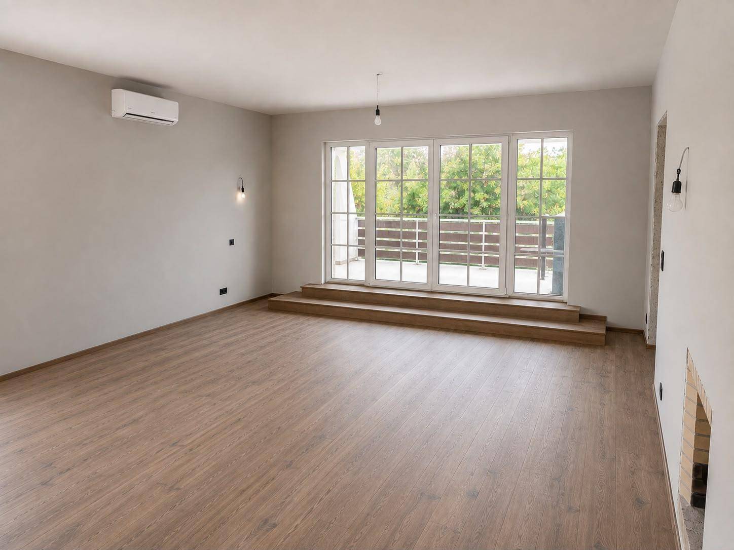 Geräumiges, helles Wohnzimmer mit Holzboden, Klimaanlage und Zugang zu einer Terrasse.