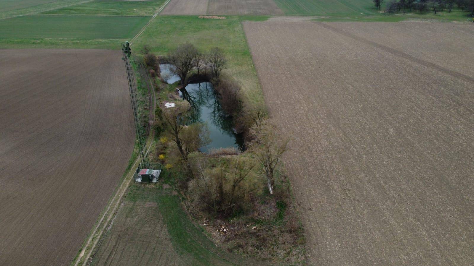 Übersicht aus der Vogelperspektive auf Ackerland mit zwei Teichen und einem schmalen Grünstreifen.