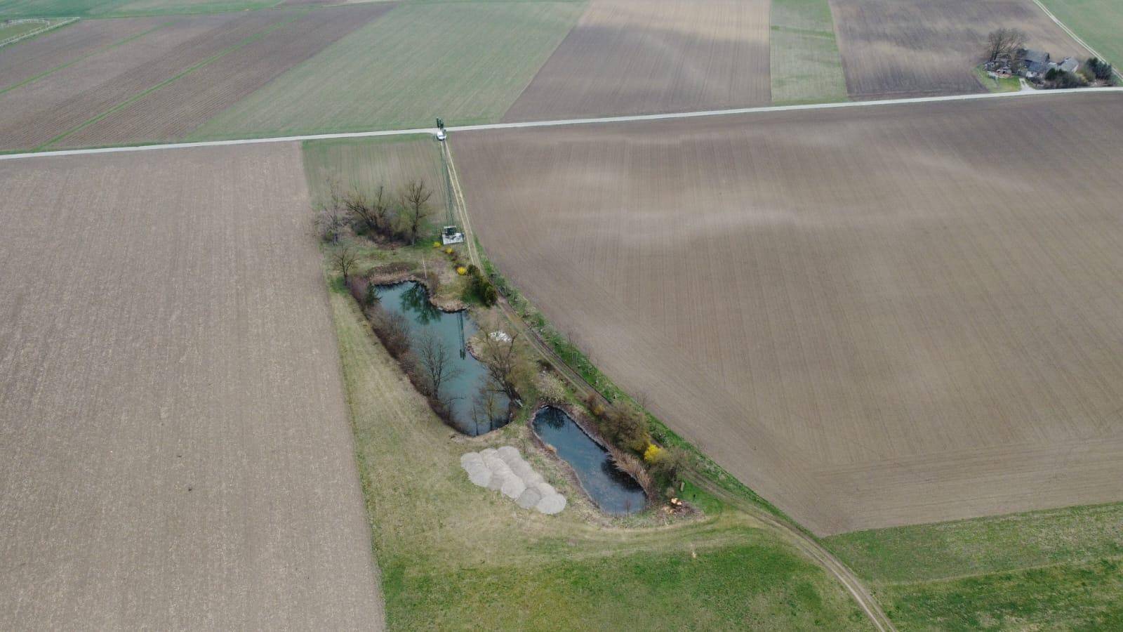 Weitwinkel-Luftaufnahme von zwei Teichen in einer landwirtschaftlich genutzten Landschaft.