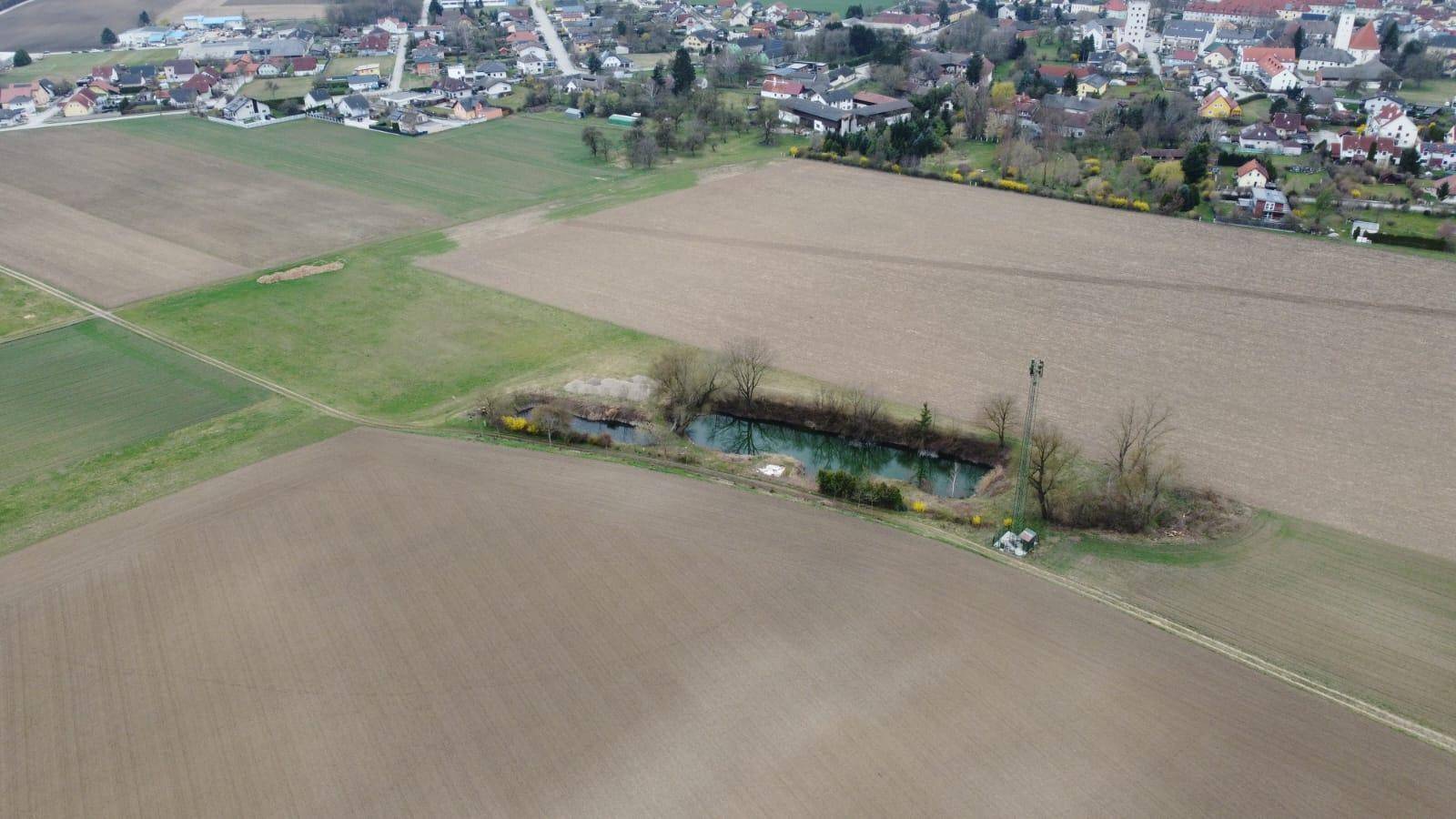 Luftaufnahme der Teiche in ländlicher Umgebung mit einem Dorf in der Ferne.