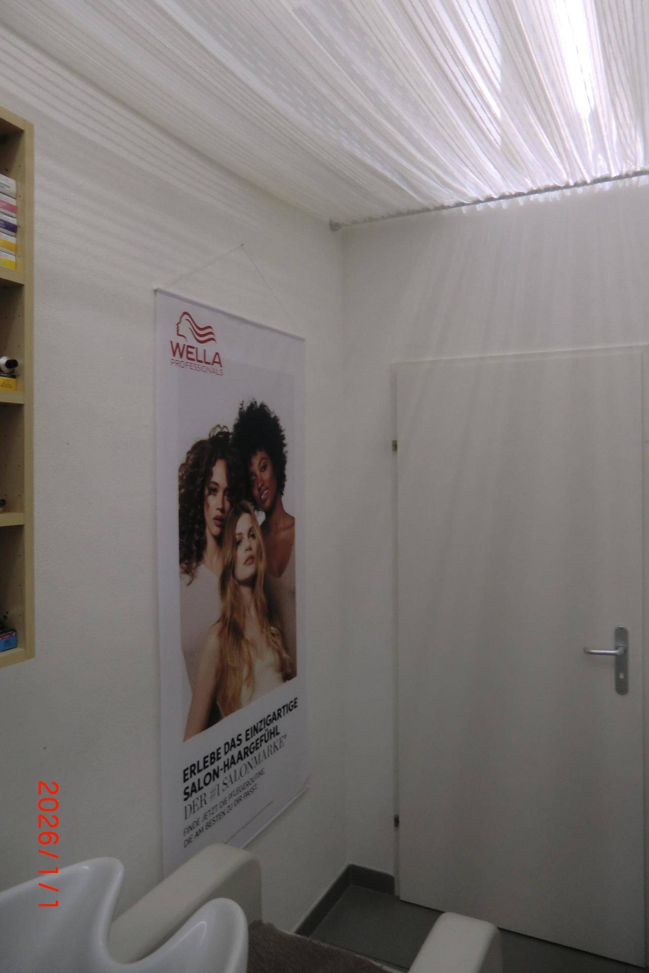 Deckenansicht mit Beleuchtung und Werbebanner an der Wand in einem Friseursalon.