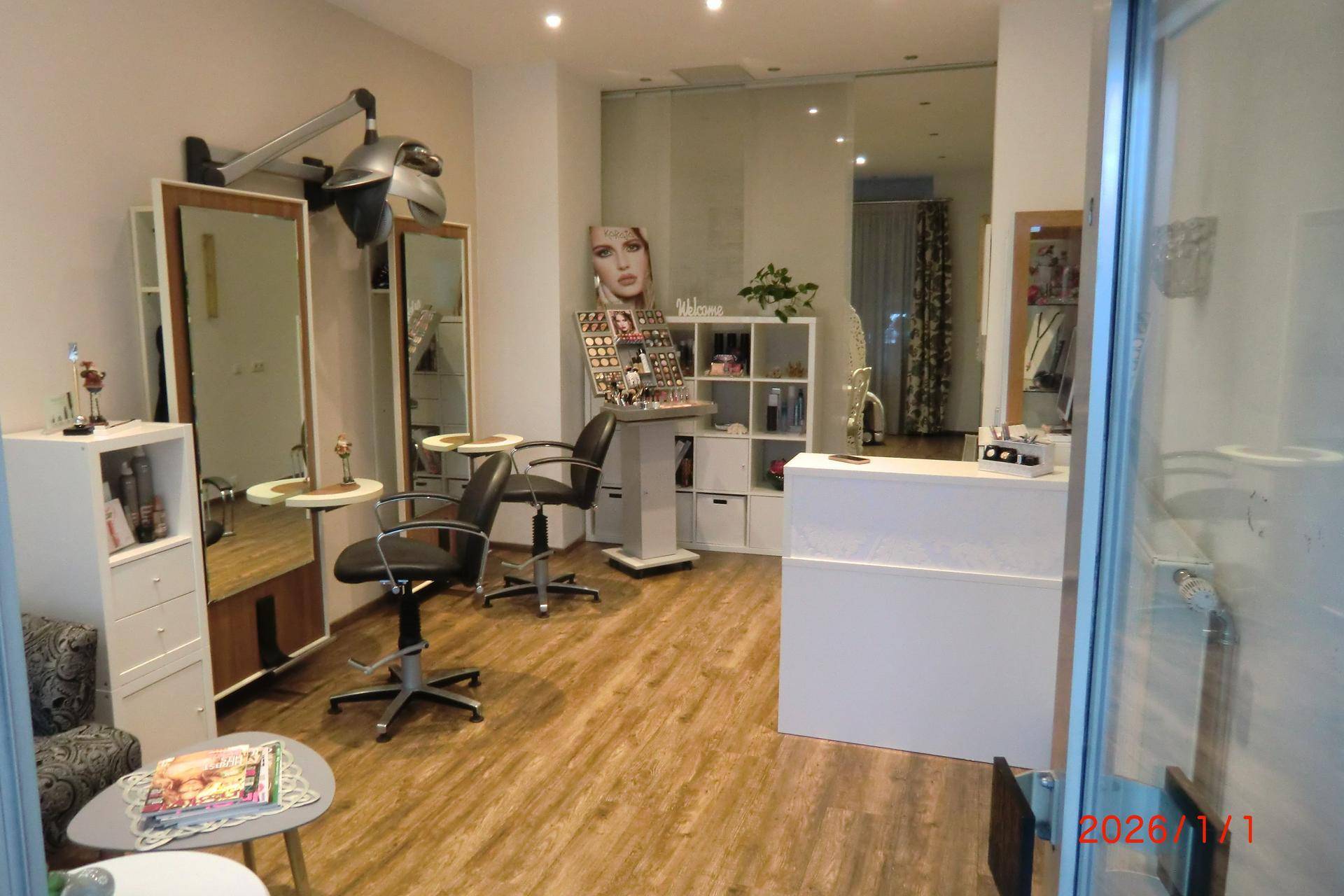 Eingangsbereich eines Friseursalons mit Empfangstheke, Bedienplätzen und Blick nach draußen.