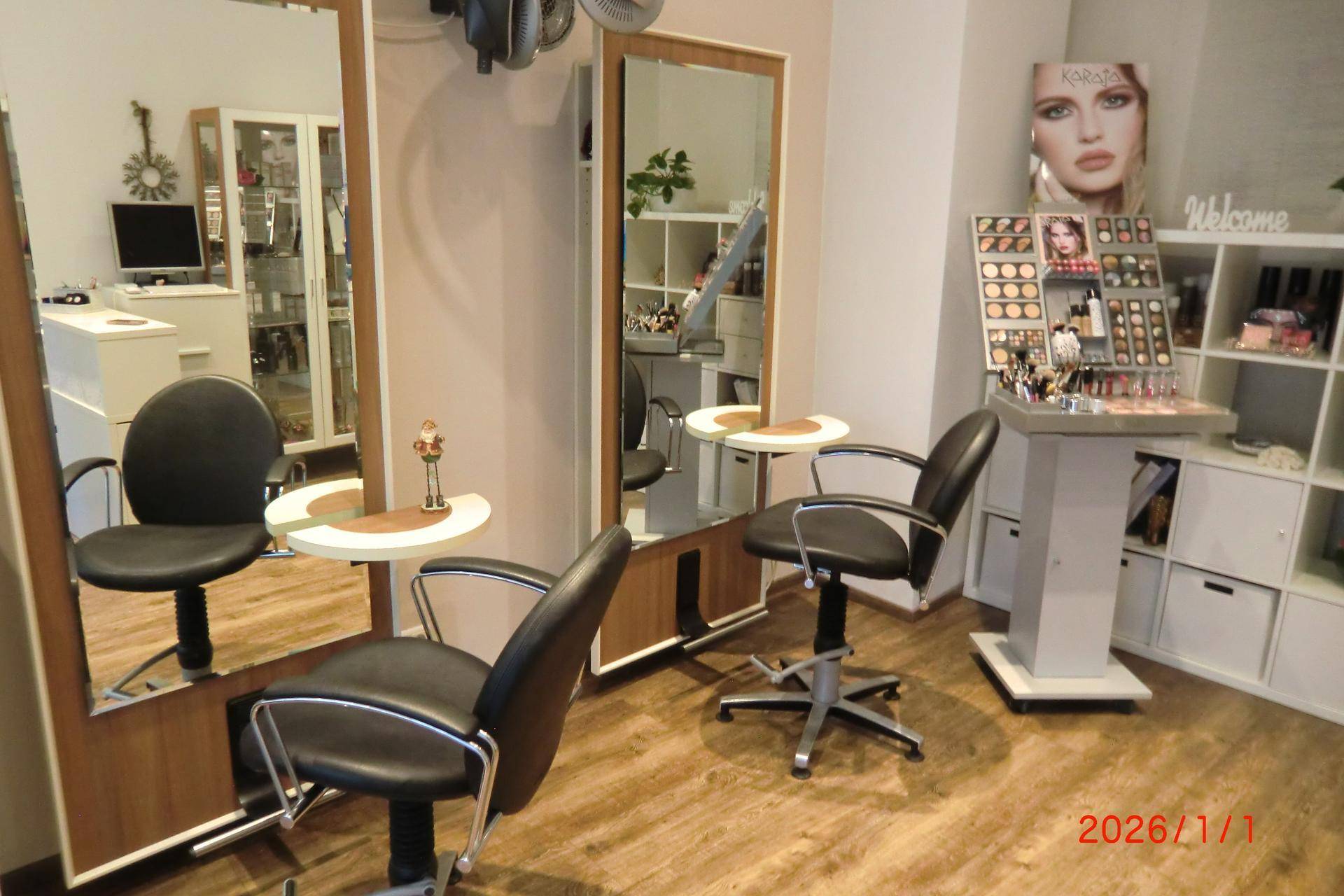 Detailansicht eines Bedienplatzes im Friseursalon mit großem Spiegel, Stuhl und Produktpräsentation.