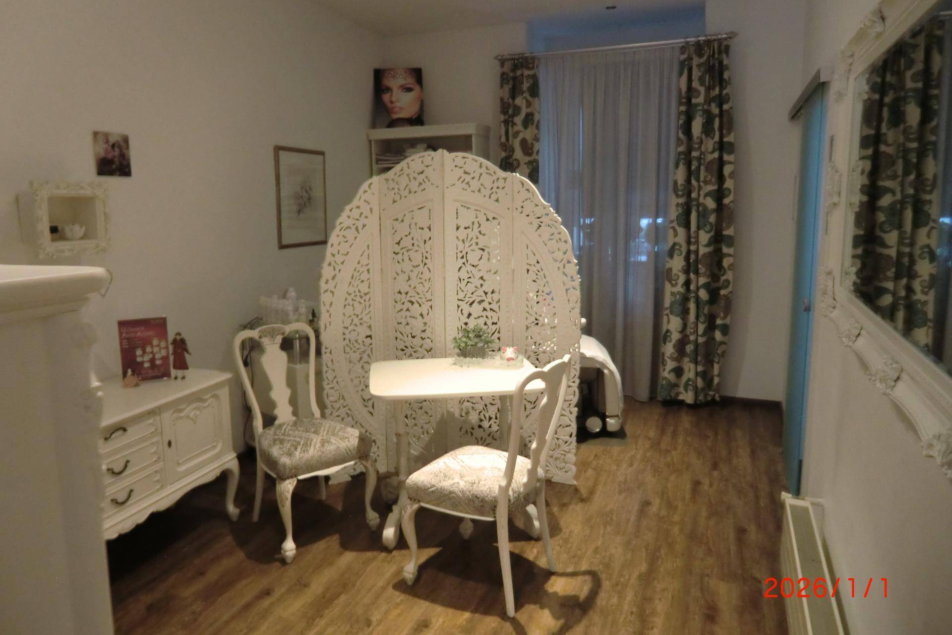Behandlungsbereich mit dekorativem Paravent, eleganten Stühlen und Holzboden im Salon.
