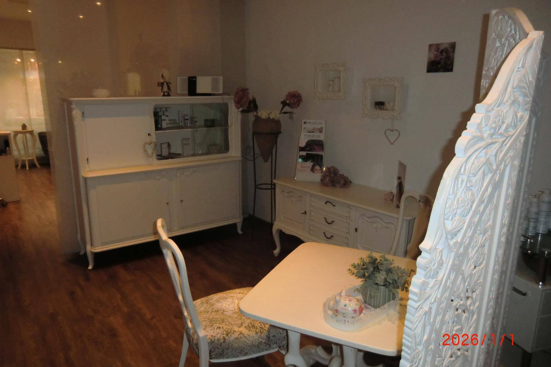 Ansicht des Behandlungsbereichs mit eleganten Möbeln, Paravent und Holzboden im Salon.