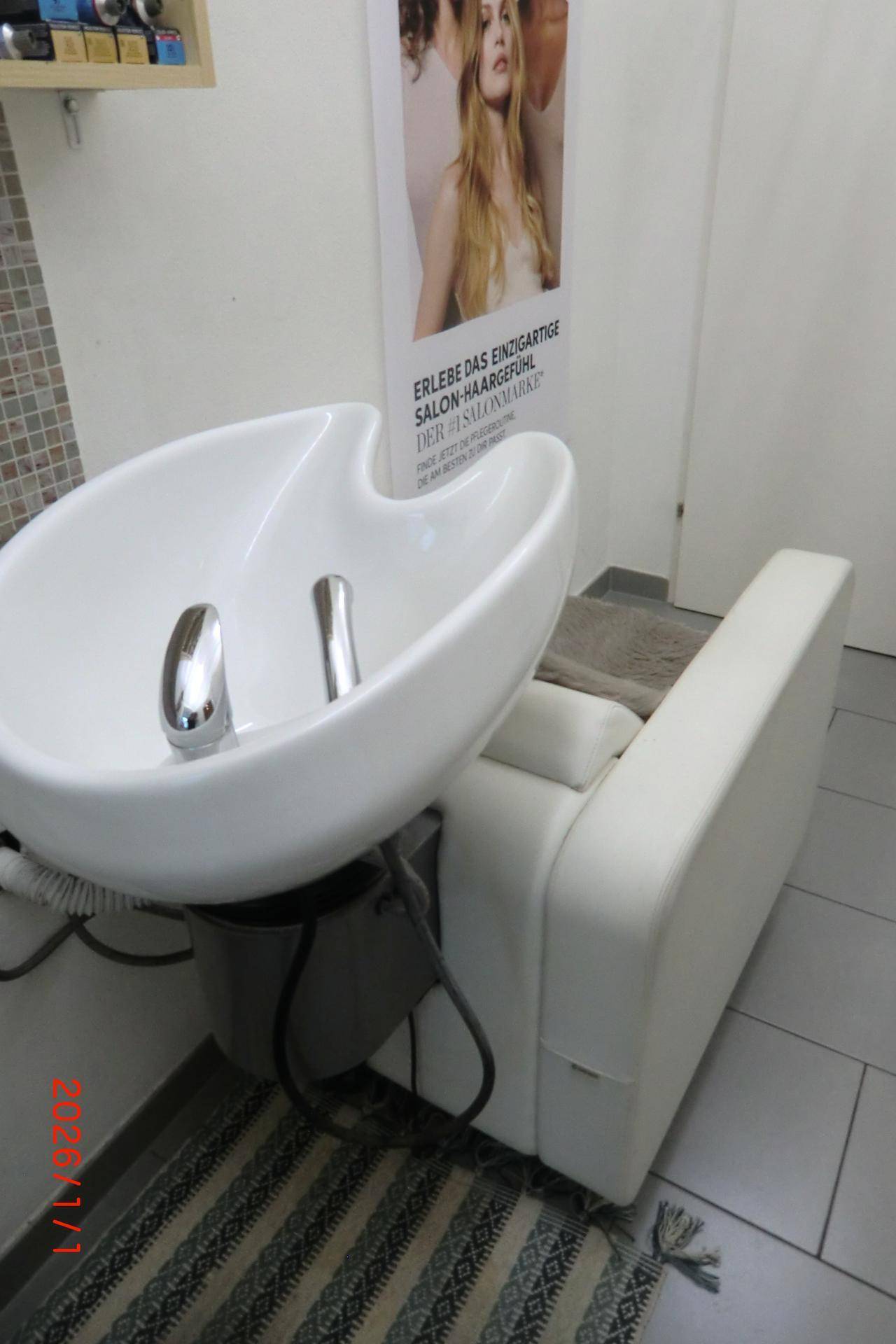 Haarwaschbecken mit passendem Stuhl und Fliesenboden in einem Friseursalon.