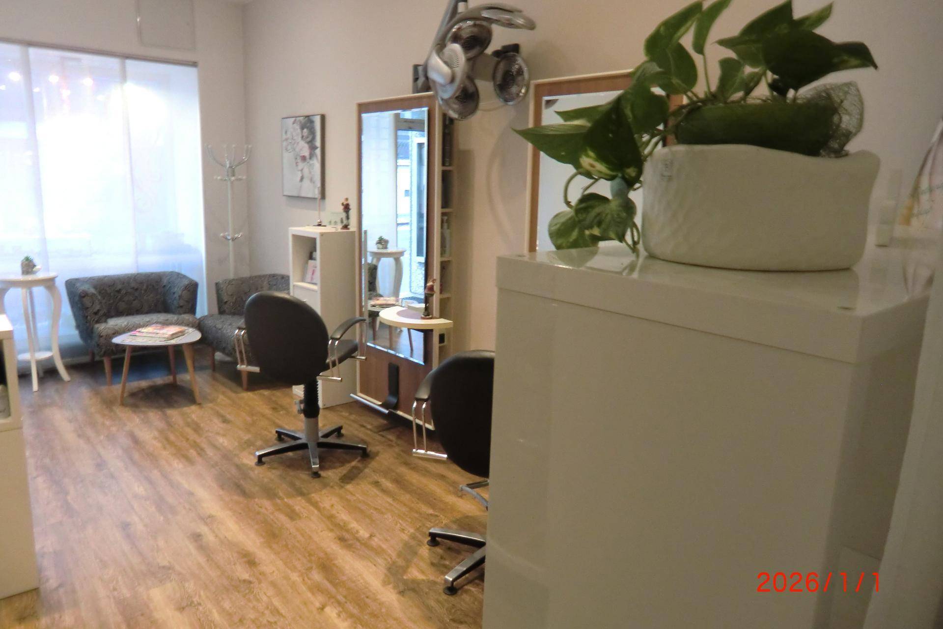 Wartebereich und Bedienplätze im Friseursalon mit bequemen Sesseln und hellem Ambiente.