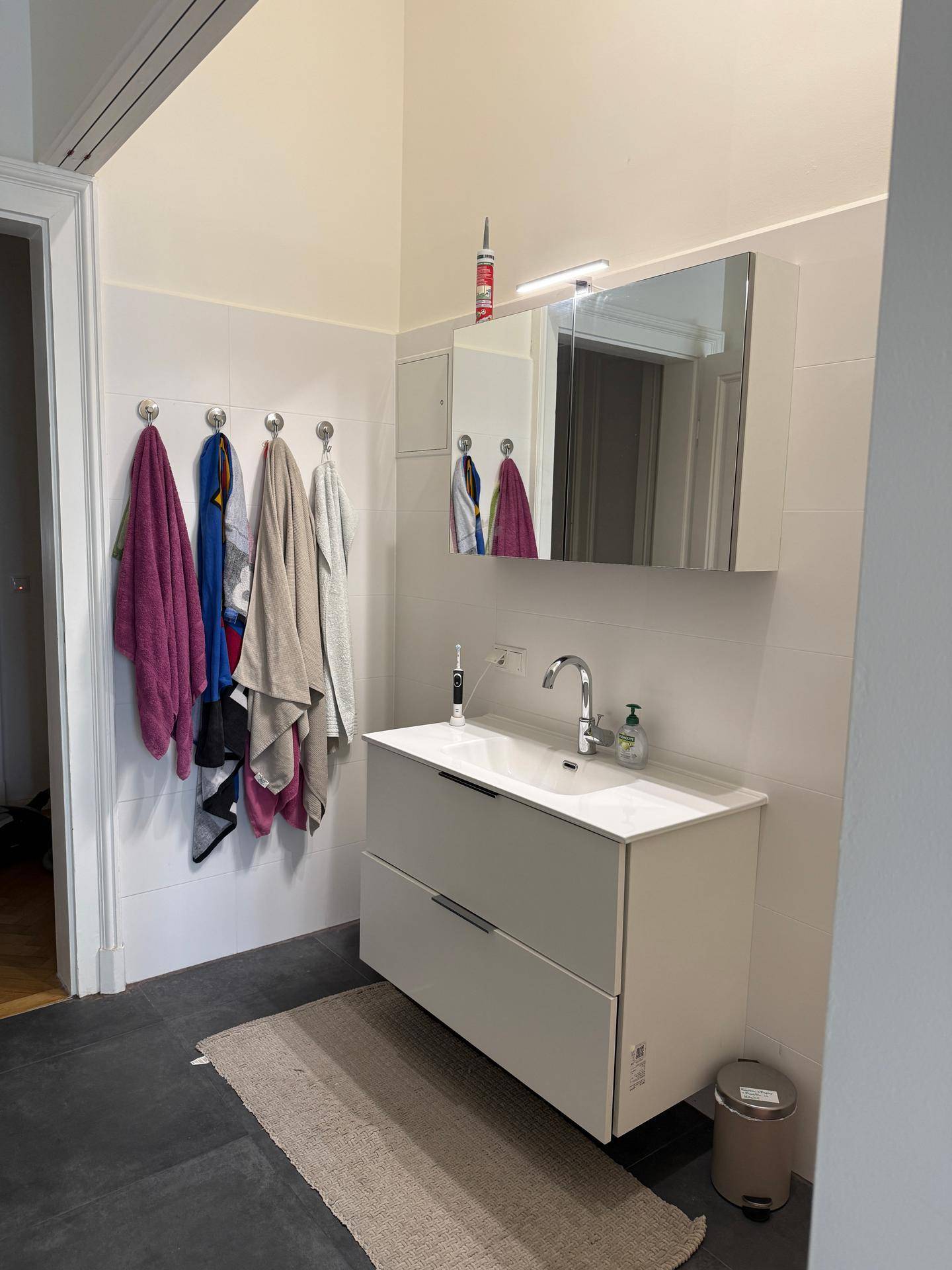 Modernes Badezimmer mit Waschtisch, Spiegelschrank und weißen Fliesen, sehr gepflegt.