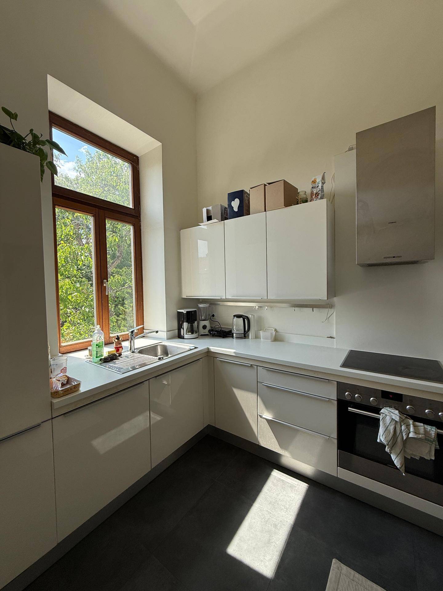 Helle Küchenzeile mit Spüle, weißen Schränken und Fenster mit Blick ins Grüne.