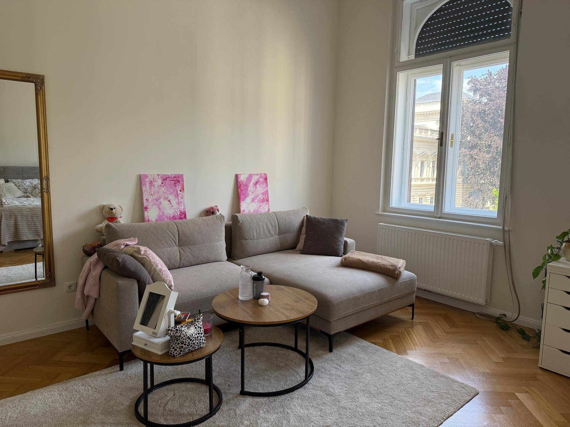 Gemütlicher Wohnbereich mit beigem Sofa, Couchtischen und Fenster mit Blick nach draußen.