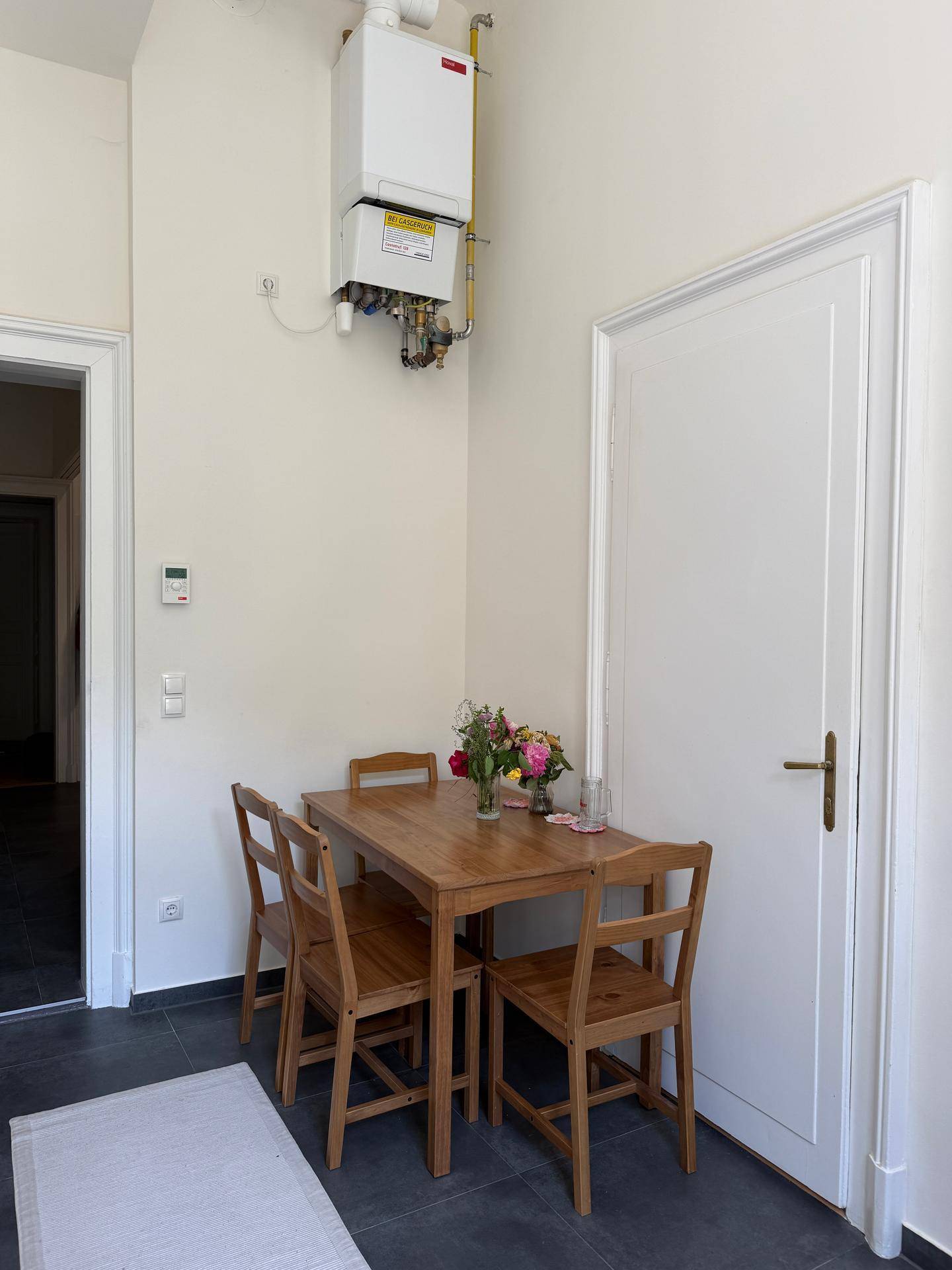 Essbereich in der Küche mit Holztisch und Stühlen unter einem Heizkessel an der Wand.