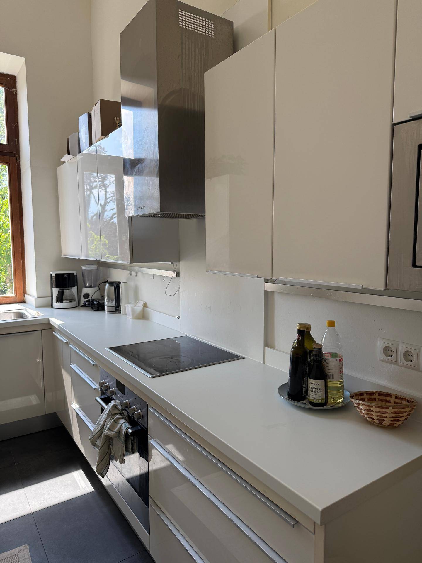 Moderne Küche mit weißen Hochglanzfronten, Induktionskochfeld und Dunstabzugshaube.