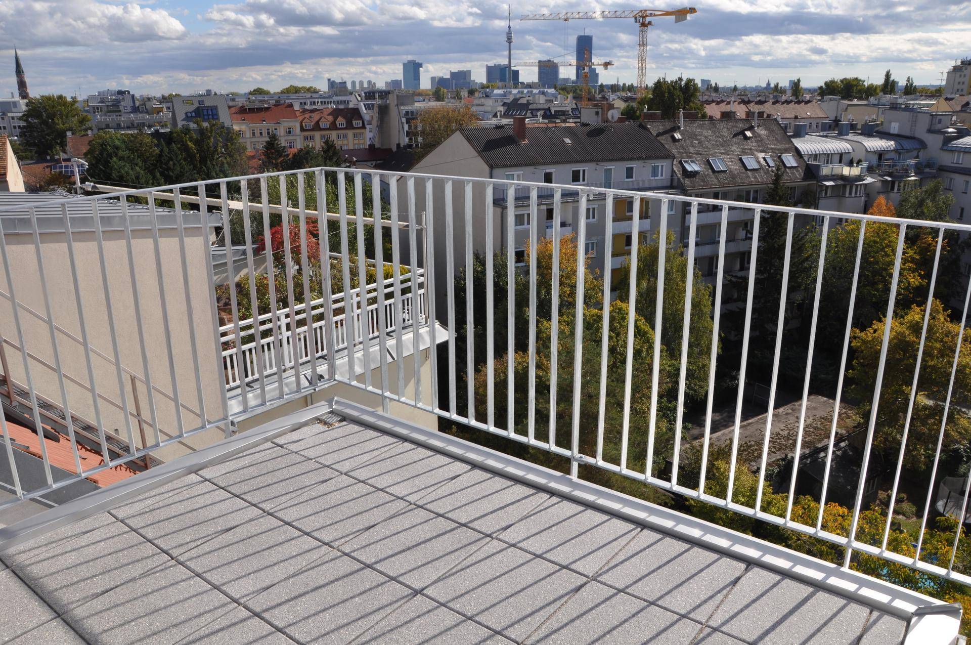 Geräumiger Balkon mit Metallgeländer und Panoramablick über die Dächer der Stadt.