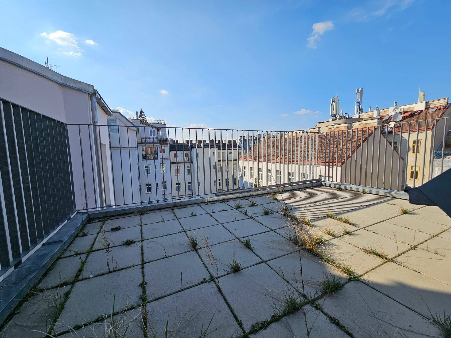 Dachterrasse mit Fliesenboden und Blick über die umliegenden Dächer der Stadt.