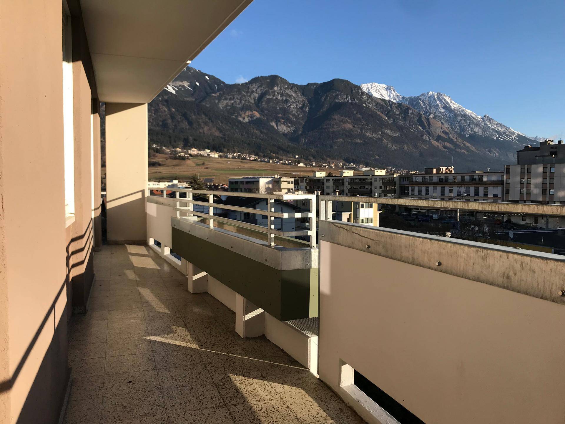 Geräumiger Balkon mit Fliesenboden und beeindruckendem Bergblick unter blauem Himmel.