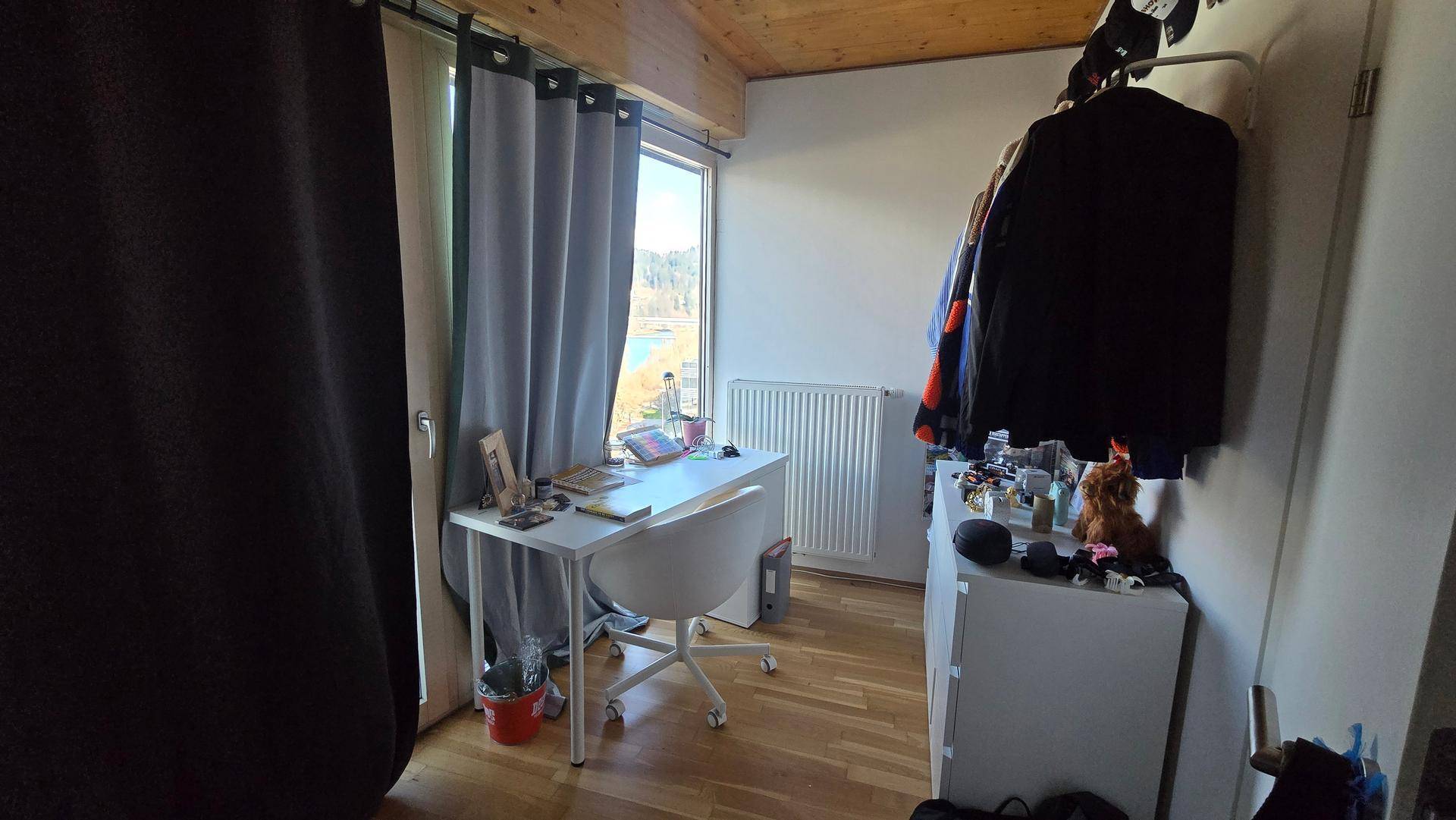 Arbeitsbereich mit Schreibtisch, Stuhl und Fenster, Holzboden und Holzdecke.