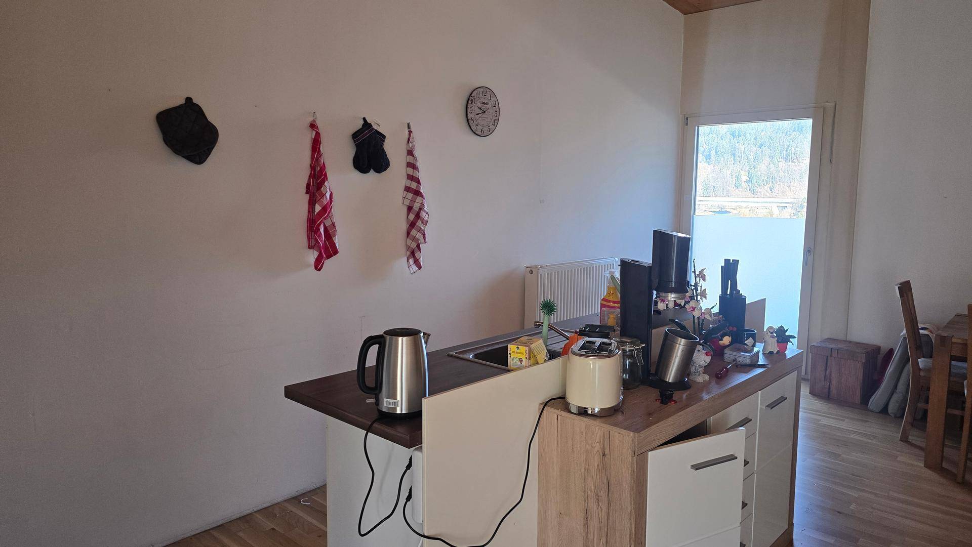 Funktionale Küche mit Arbeitsplatte, Spüle und Blick auf das Wasser durch das Fenster.