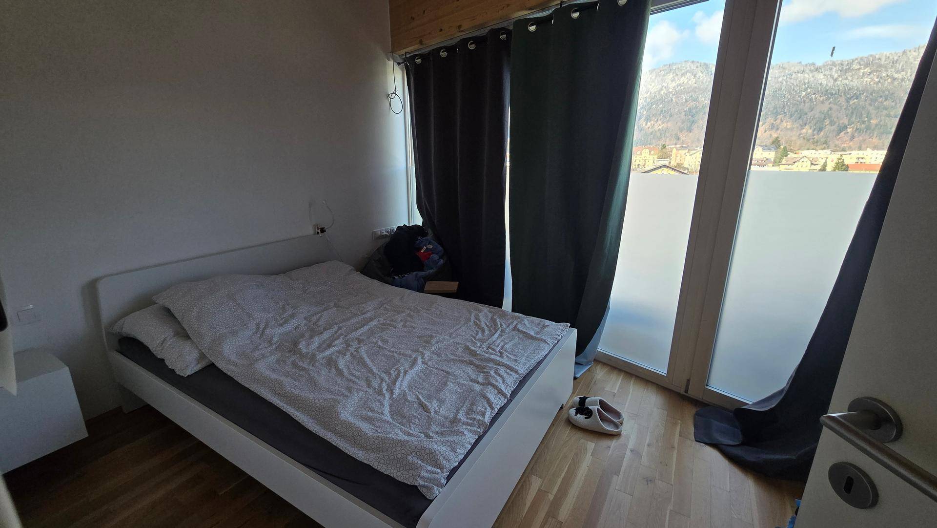 Schlafzimmer mit Einzelbett, Holzboden und Holzdecke, großes Fenster mit Blick.