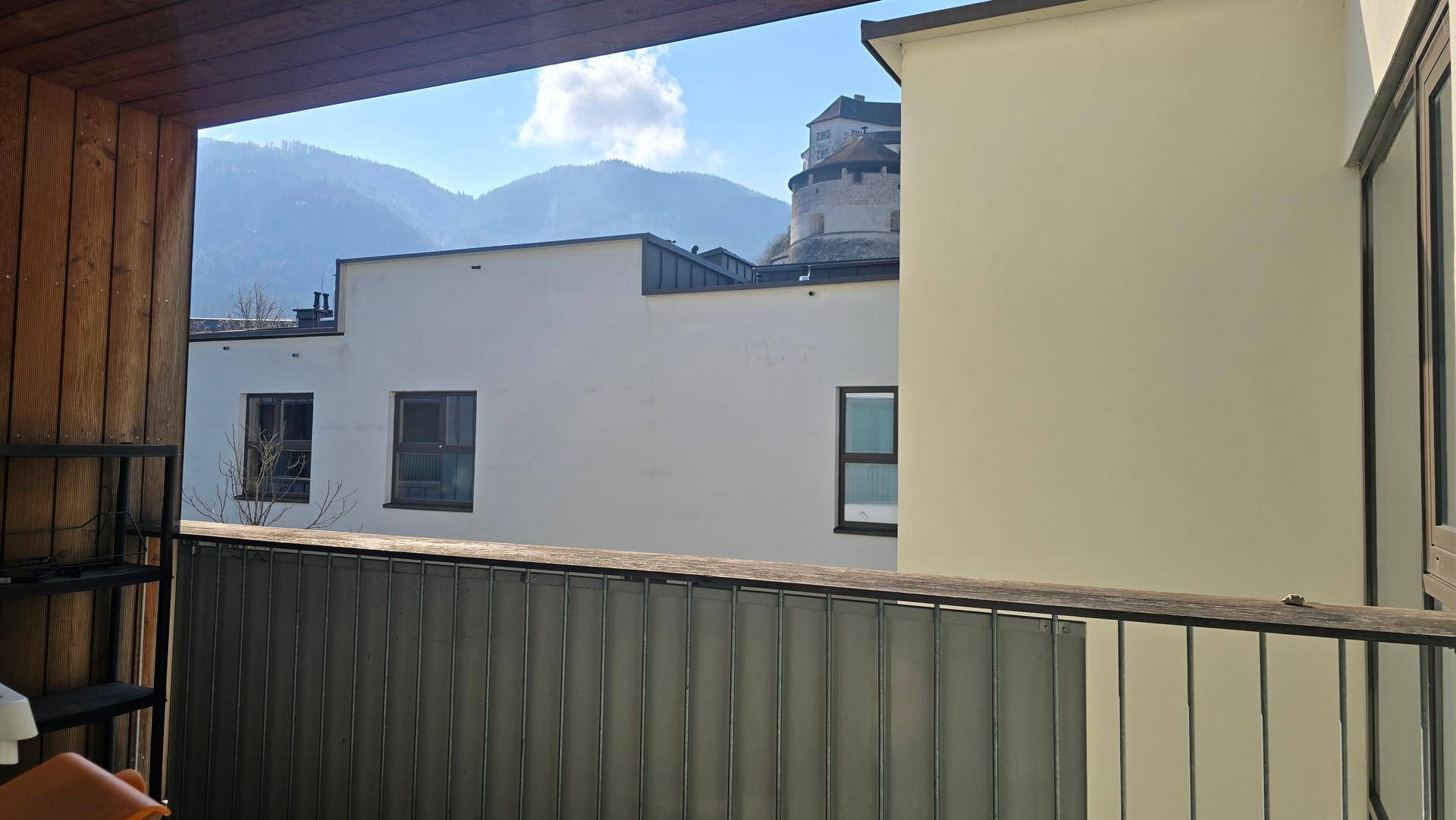 Balkon mit Blick auf ein Gebäude und eine Burg auf dem Berg im Hintergrund.