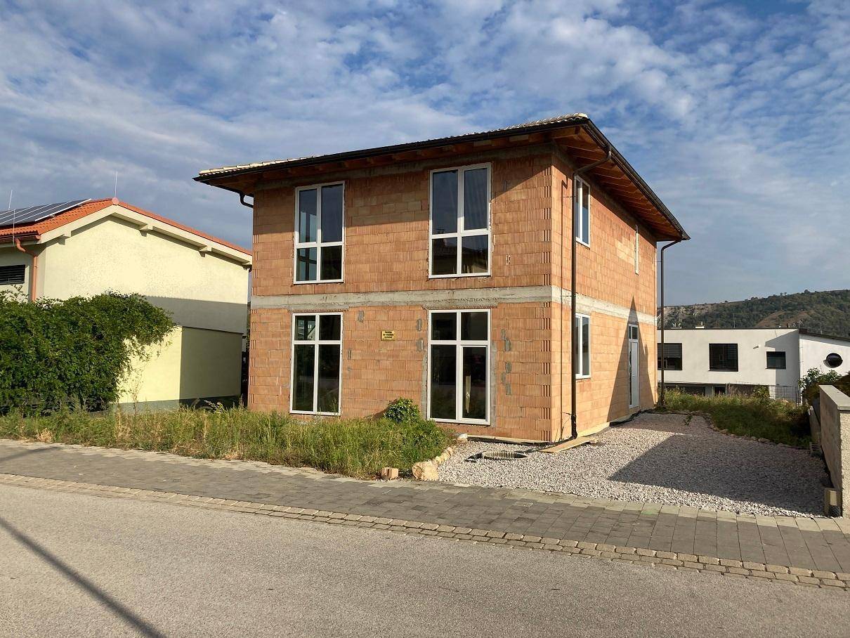 Neubau eines Einfamilienhauses in Massivbauweise mit großen Fenstern und sichtbaren Ziegelwänden.