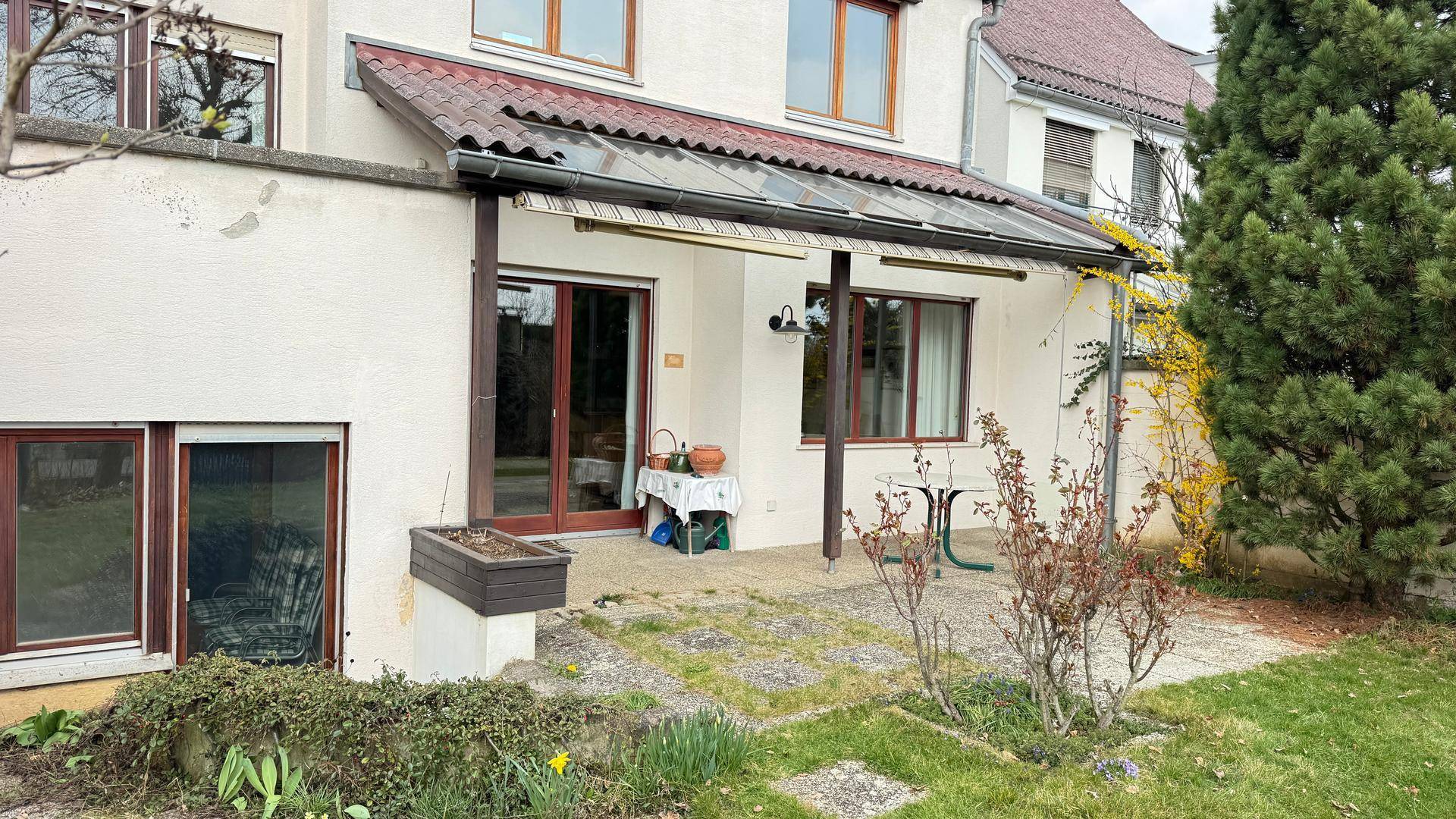 Überdachte Terrasse mit Sitzgelegenheiten und direktem Zugang zum Garten.