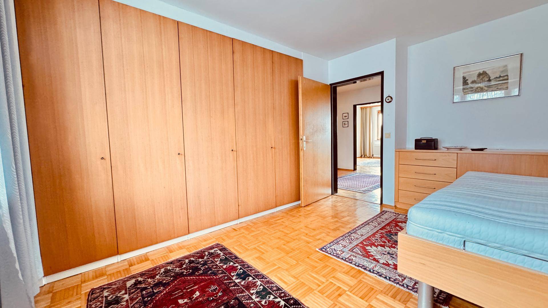 Schlafzimmer mit Einbauschränken, Einzelbett und Parkettboden.
