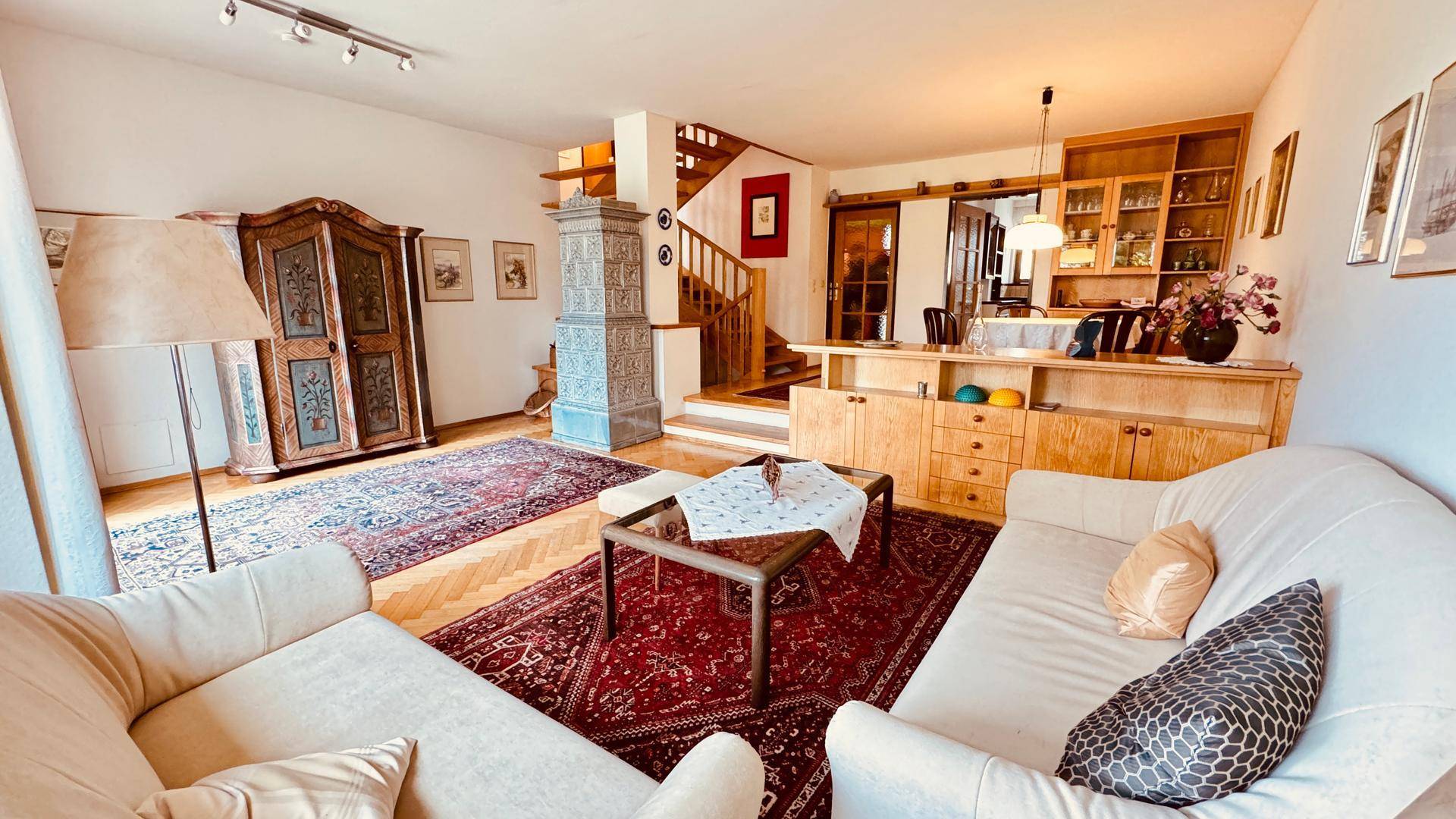 Gemütliches Wohnzimmer mit traditionellem Kachelofen, Parkettboden und Holzmöbeln.