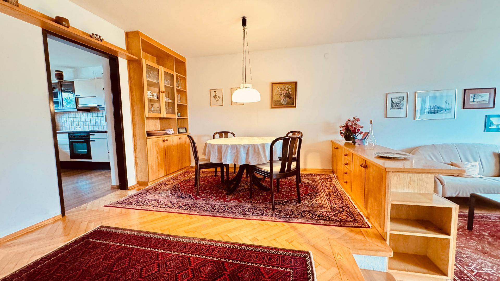 Essbereich mit Holztisch und Stühlen, offen zum Wohnzimmer und mit Blick in die Küche.