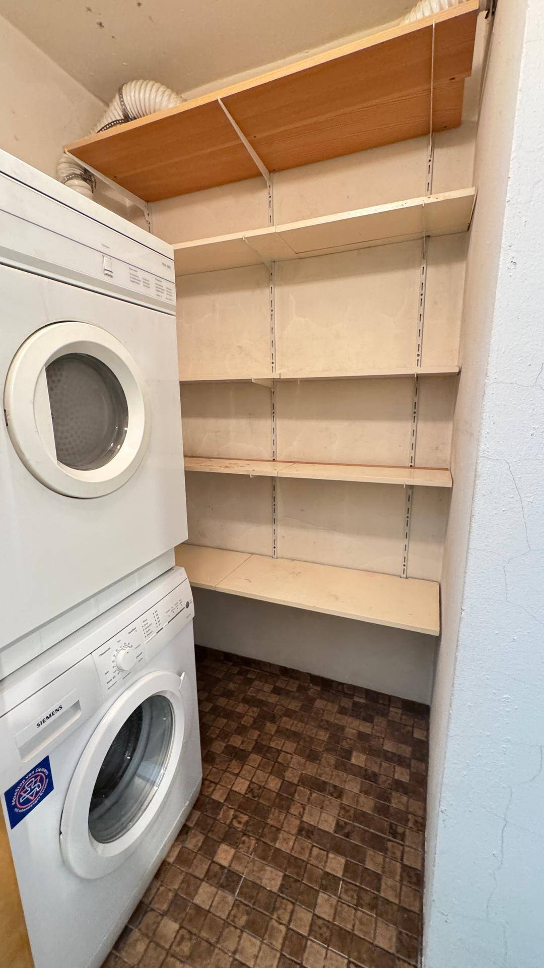 Hauswirtschaftsraum mit Waschmaschine, Trockner und praktischen Regalen.