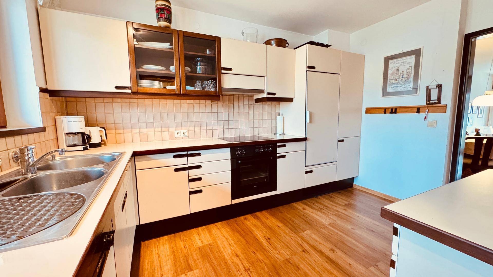 Küche mit integriertem Kühlschrank, hellen Schränken und Fliesenrückwand.