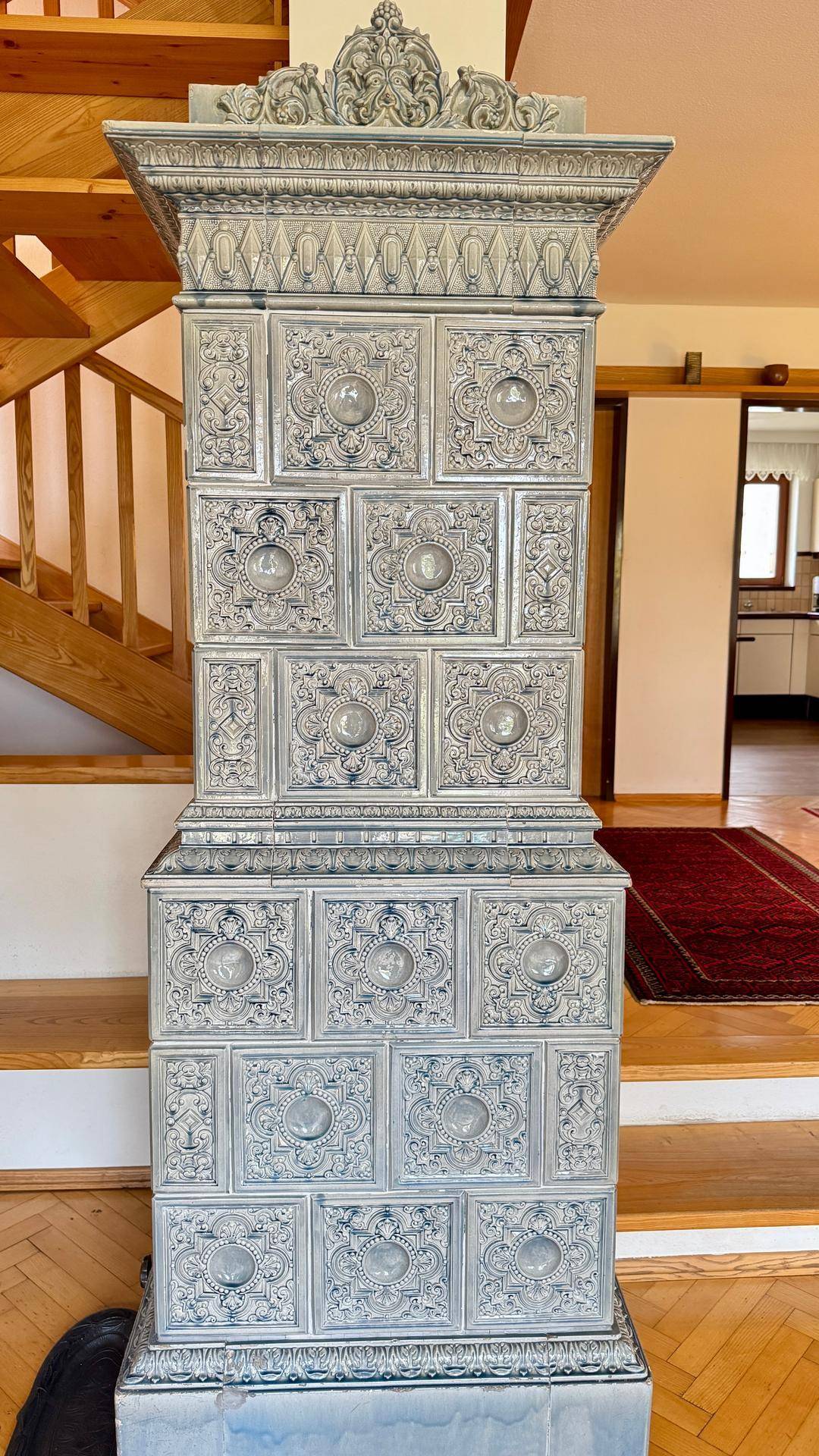 Detailaufnahme des kunstvoll verzierten, traditionellen Kachelofens als zentrales Element.