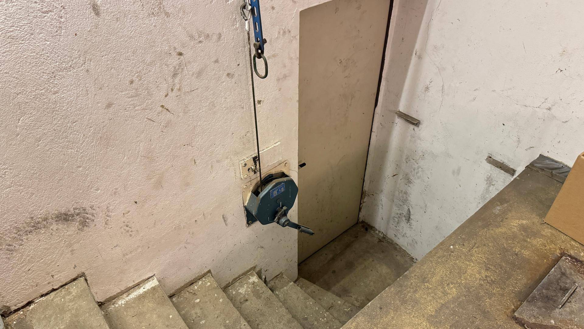 Kellertreppe mit einer an der Wand montierten Winde.