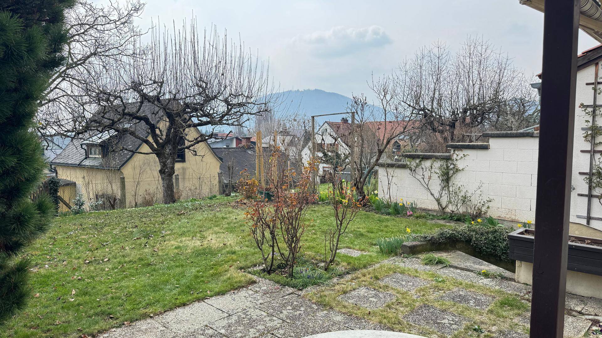 Gartenbereich mit Rasenfläche und Blick auf die umliegende Landschaft und Berge.