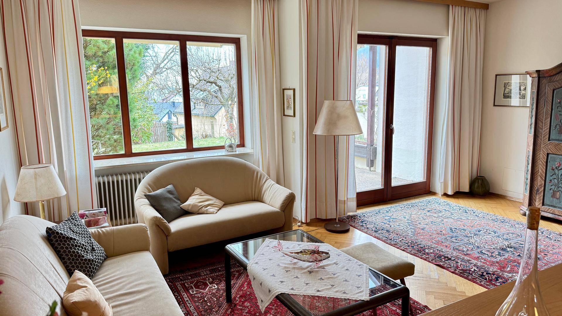 Helles Wohnzimmer mit bequemen Sofas, Parkettboden und direktem Zugang zum Außenbereich.