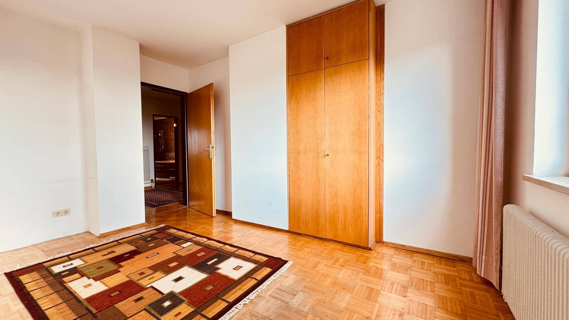 Leeres Zimmer mit Einbauschrank und Parkettboden.