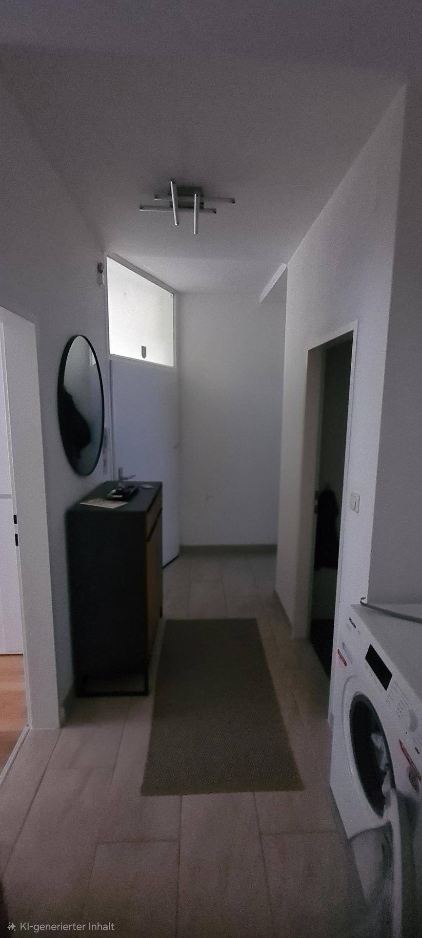 Heller Flur mit Waschmaschine, einem Spiegel und Fliesenboden.