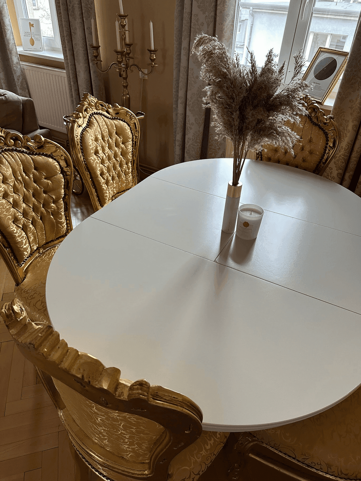 Heller Essbereich mit ovalem Tisch und opulenten goldenen Stühlen, umgeben von natürlichem Licht.