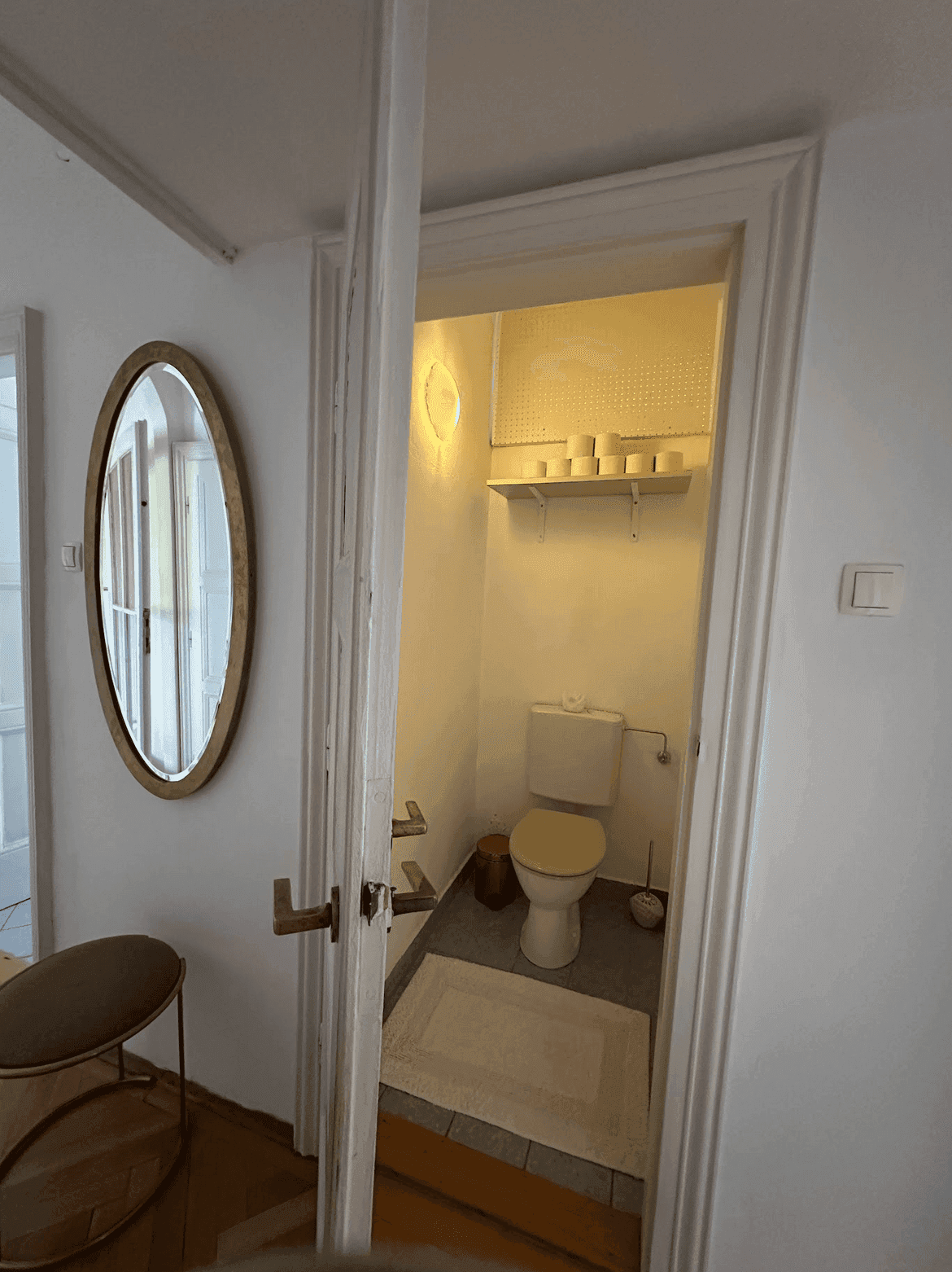 Kleines Gäste-WC mit Toilette und einem Regal, zugänglich vom Flur aus.